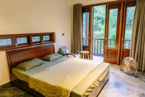 ein Schlafzimmer mit einem großen Bett und einem Balkon in der Unterkunft Leela Village - Playground For Buddhas in Hanoi