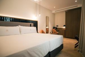 a bedroom with a large white bed and a desk at Legado Magdalena Hotel in Seville