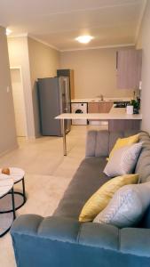 a living room with a blue couch and a kitchen at Midrand Serene Escape in Midrand