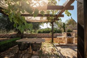 a table and chairs under a pergola in a garden at Trullo Due Ulivi in Monopoli