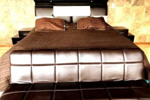 a large bed with a brown comforter and pillows at Views from the Heart of theForest ,Wi-Fi, TV, Terrace in Mexico City