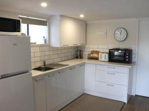 a kitchen with white cabinets and a clock on the wall at Hidden Gem for business traveller's in Tauranga
