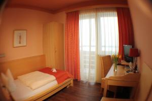1 dormitorio con cama, escritorio y ventana en AKZENT Hotel Landgasthof Murrer, en Straubing