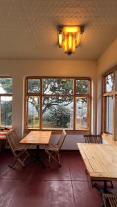 Habitación con 2 mesas de madera y ventanas. en Fishbird Art Deco Villa, en Johannesburgo