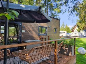 eine Terrasse mit 2 Stühlen und einem Sonnenschirm in der Unterkunft Tiny House w Camp Gorący Potok in Szaflary