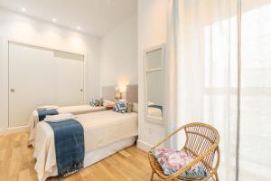 - une chambre avec un lit, une chaise et une fenêtre dans l'établissement Magno Apartments Casa del Correo Mayor II, à Séville