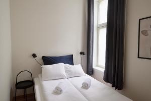um quarto com uma cama com lençóis brancos e uma janela em Grünerløkka Deluxe Apartments em Oslo