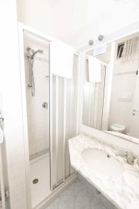 a white bathroom with a shower and a sink at Hotel Saint Louis in Rimini