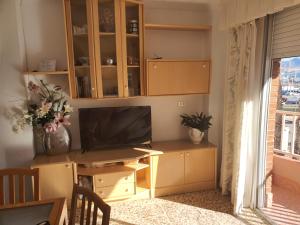 a living room with a desk with a tv and a window at Adorable Apartamento en la Playa in Puerto de Mazarrón