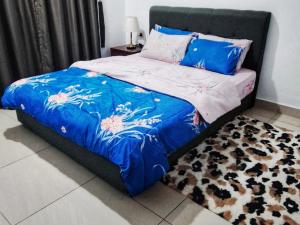 a bed with a blue comforter and a rug at D Casa Cattleya Desaru in Kota Tinggi +20 photos