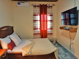 a small bedroom with a bed and a television at RESIDENCE DORANA in Kribi