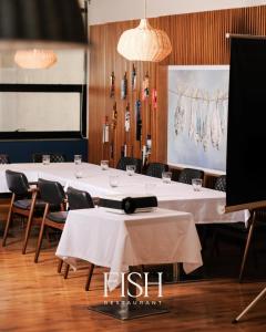 une salle à manger avec des tables, des chaises et un tissu de table blanc dans l'établissement HOTEL 12, à Gjakove