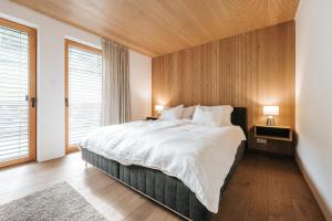 a bedroom with a large bed with a wooden wall at Villa Seeblick - Your Austrian Home in Altaussee