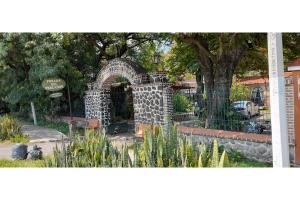 a stone archway in a park with a tree at Capital O Posada Del Pescador in Chapala