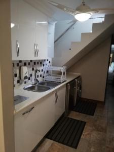 a kitchen with a sink and a staircase at 94 Sea Cottage in Mossel Bay