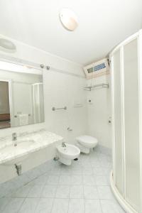 W łazience znajduje się umywalka, toaleta i lustro. w obiekcie Hotel Saint Louis w Rimini