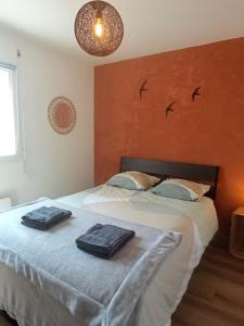 zwei Handtücher auf einem Bett in einem Schlafzimmer mit Vögeln an der Wand in der Unterkunft A 50 m de la plage, appartement de 35 m2 : Les pieds salés in Bréhal