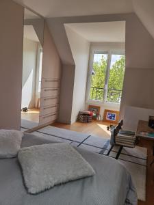 een slaapkamer met 2 bedden, een bureau en ramen bij 2 chambres dans maison familiale jardin et spa in Noisy-le-Roi