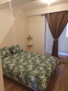 a bedroom with a bed with a green comforter and a window at Jolie T3 avec terrasse in Carcassonne