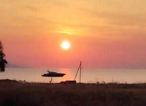 een boot in het water met een zonsondergang op de achtergrond bij STUDIOS POSEIDONIA apartments 50 & 70 sqm with sea view in Korinthos