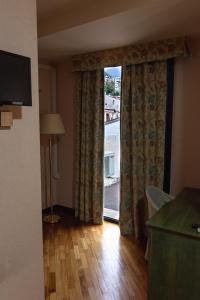 Habitación con ventana grande con cortinas y suelo de madera. en Hotel San Nicola en Lagonegro