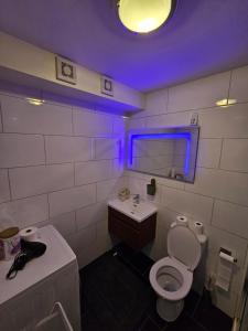ein Badezimmer mit einem WC, einem Waschbecken und einem lila Licht in der Unterkunft Entire 2 bed Flat Ela Rosa fully serviced in Elmers End