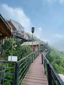 un passaggio pedonale in legno su una collina con un edificio di Táo Homestay Venuestay a Bắc Yên