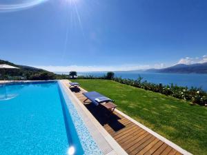トッリ・デル・ベーナコにあるMINI DI LUSSO CON PISCINAの水辺の景色を望むスイミングプール(椅子付)
