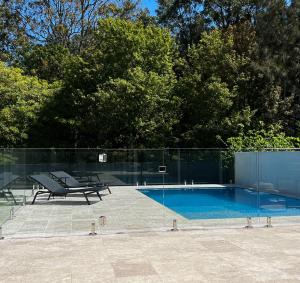 a swimming pool with a bench next to a fence at The Heads House in Shoalhaven Heads