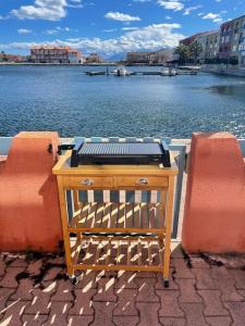 a wooden table sitting next to a body of water at La Casita ,Appartement face à l’étang in Le Barcarès