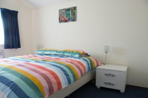 een slaapkamer met een bed met een kleurrijk gestreept dekbed bij Fries Vakantiehuis, grote tuin, nabij het Pikmeer in Grou