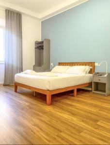 uma cama grande num quarto com piso em madeira em Lexie Suites em Roma