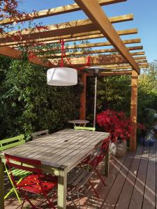 een houten tafel en stoelen op een terras met een pergola bij 2 chambres dans maison familiale jardin et spa in Noisy-le-Roi