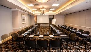 a conference room with long tables and chairs and a screen at Southern Sun Maputo in Maputo +48 photos