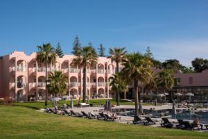 un grande edificio rosa con palme e piscina di Vila Gale Collection Praia ad Albufeira