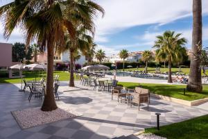 a patio with tables and chairs and palm trees at Vila Gale Collection Praia in Albufeira