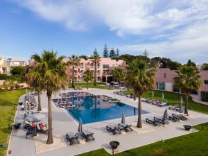 an aerial view of a resort pool with palm trees and chairs at Vila Gale Collection Praia in Albufeira