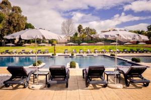 a pool with chairs and tables and umbrellas at Vila Gale Collection Praia in Albufeira