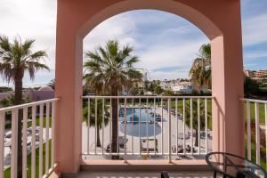 a balcony with a view of a pool and palm trees at Vila Gale Collection Praia in Albufeira