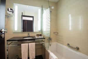 a bathroom with a sink and a tub and a mirror at Vila Gale Collection Praia in Albufeira