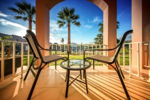 two chairs and a glass table on a balcony with palm trees at Vila Gale Collection Praia in Albufeira
