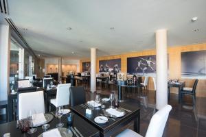 a restaurant with black tables and white chairs at Vila Gale Collection Praia in Albufeira