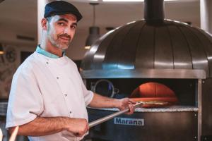 a chef preparing food in front of an oven at Vila Gale Collection Praia in Albufeira