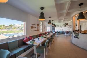 a restaurant with tables and chairs and a large window at Vila Gale Collection Praia in Albufeira