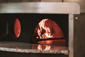 a pizza oven with a fire in it at Vila Gale Collection Praia in Albufeira