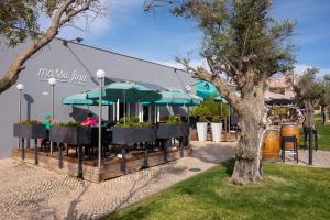 a restaurant with tables and umbrellas in a park at Vila Gale Collection Praia in Albufeira