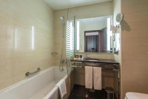 a bathroom with a tub and a sink and a mirror at Vila Gale Collection Praia in Albufeira