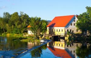 a building with an orange roof next to a river at Soba Kolovrat in Straža