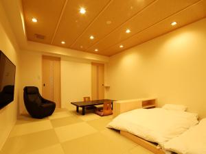 a bedroom with a bed and a chair and a table at Arima Royal Hotel in Kobe