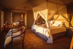 a bedroom with a canopy bed and a chair at Cha Cha Metsi in Maun